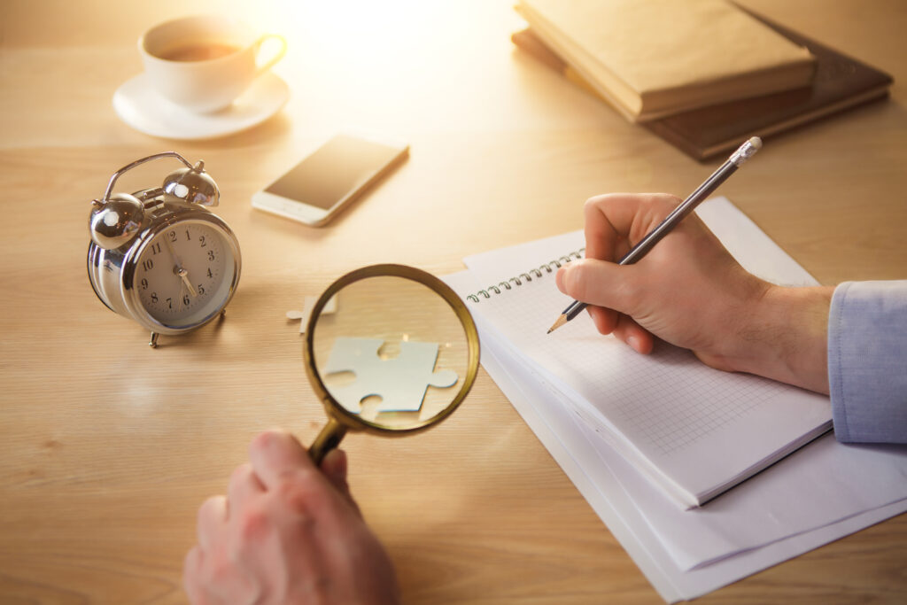 the male hands with a pencil and magnifying glass